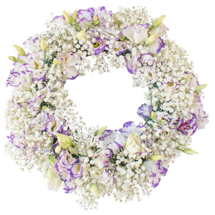In this image, a meticulously crafted funeral wreath appears almost to float against a spotless white backdrop, its round form perfectly balanced and richly textured. The foundation of the wreath is created from thick clusters of white Baby's Breath, each spray branching into dozens of pinhead blooms that together resemble a ring of soft foam or a delicate cloud circling the open centre. Interwoven with this airy base are generous stems of Lisianthus, the flowers positioned so that their ruffled heads sit slightly above the Gypsophila, creating gentle undulations around the ring. The Lisianthus petals are a calm, milky white through the centre of the bloom, while the edges are finely brushed with tones of purple and lavender, like ink bleeding softly into paper. Some blossoms are fully unfurled, revealing layered, cup-shaped centres with deeper shadows, while others are just opening or still in bud, pale green and cream with only a suggestion of the purple edging to come. There are no leaves or bold foliage to distract from the simplicity of the palette; instead, everything focuses on this interplay of white, soft lilac and violet. The circle's centre is sharply defined yet empty, enhancing the symbolic message of continuity, remembrance and the unending nature of love. Lit with even, diffused light, the flowers show true-to-life colours and a velvety texture that suggests cool, fresh petals to the touch. It is the sort of thoughtfully arranged tribute a family in Golders Green might select for a graveside service at a local cemetery, or for a memorial table in a quiet home near the high street, offering an atmosphere of peace, grace and gentle farewell.