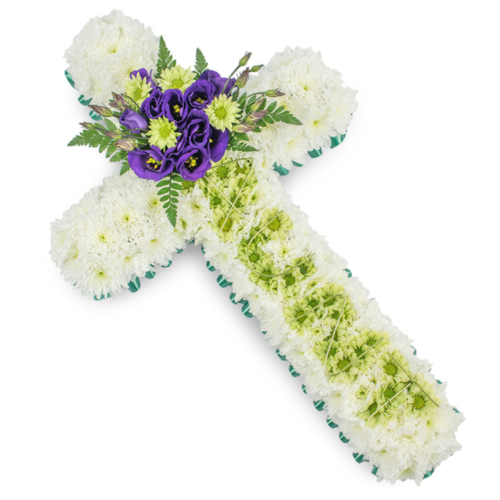 A dignified floral cross tribute is displayed in full view, its carefully balanced colours and textures captured against a bright white background that highlights every petal and leaf. The main body of the cross is entirely carpeted in small white chrysanthemums, each bloom placed snugly beside the next so that the surface appears smooth and softly padded, like a comforting quilt of white. These blossoms form the horizontal arms and the long vertical stem without any gaps, lending the arrangement a sense of calm order and reverence. Neatly framing this field of white is a narrow border of vivid green ribbon or close-set greenery, which traces around the entire perimeter of the cross and subtly defines its outline, rather like the trim on a hand-finished garment. Down the middle of the vertical arm runs a striking inset of lime green button chrysanthemums, their rounded centres forming a clear, fresh stripe that stands out from the white yet remains gentle on the eye. Fine, pale green or silver wires are threaded over this central strip in a light criss-cross pattern, adding a layer of texture and craftsmanship. At the very centre, where the cross's arms meet, a richly coloured cluster of deep purple lisianthus, bright lime green blooms, and softly arching fern fronds provides a natural focal point. The lisianthus petals are slightly ruffled, with a velvety appearance that feels luxurious yet restrained. Created as a sympathy tribute by Flowers Golders Green for services in local churches and chapels near Golders Hill Park or Hoop Lane crematorium, this floral cross offers a gentle yet eloquent expression of faith, remembrance, and enduring affection.