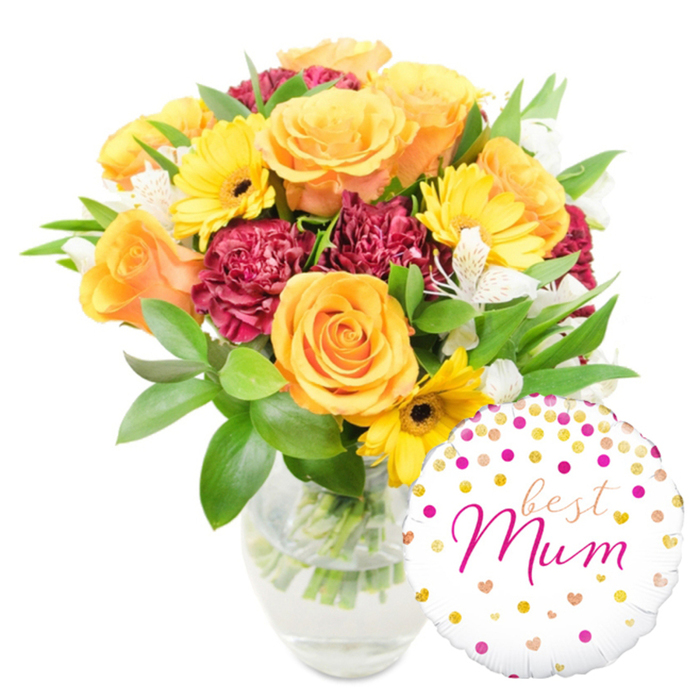 Captured against a clean white surface, this arranged bouquet and balloon set feels both celebratory and tender, its left-centred composition balanced by a round foil balloon at the lower right. The arrangement is anchored by several large, peachy-orange roses-each blossom open and layered-whose soft velvety petals create a warm, tactile centre. Bright yellow gerbera daisies are threaded through the design, their broad rays and dark centres providing joyful punctuation and a lively contrast to the roses. Deep maroon or burgundy carnations add plush volume and a velveteen shadow that helps the warmer hues sing. Intermittent sprays of white alstroemeria lift the palette with delicate, speckled petals that introduce a refined, almost botanical note. Lush green foliage, from glossy broad leaves to more delicate sprigs, envelops the flowers and gives the bouquet a freshly gathered look; the clear glass vase allows the viewer to see the crisp stems and clear water, reinforcing the sense of recent, careful assembly. At the bottom-right, slightly overlapping the vase, a glossy white balloon decorated with scattered gold and fuchsia polka dots and tiny hearts bears the message best Mum in flowing fuchsia script, the foil surface catching highlights and soft reflections. This composition is ideal for marking a mother's special day-a warm, garden-fresh gift that reads as both celebratory and intimate, the kind of arrangement you'd find being packaged for delivery around Golders Green, Belsize Park and neighbouring streets.