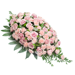 Set against a pure white backdrop, this elongated pink casket spray seems to float in stillness, its teardrop shape broad and reassuring at the top before tapering into a soft, graceful point. The arrangement is composed of an abundance of pastel blooms: large, soft pink roses with layer upon layer of silky petals form the focal points, their rounded heads opening in gentle spirals that suggest loving memories unfolding. Woven among them, smaller light peach-pink carnations provide a delicate ruffle, each fringed petal catching the light and adding a quiet movement across the surface of the spray. The colours move subtly from pale blush to slightly deeper rose tones, creating a soothing gradient rather than any jarring contrast. Around and beneath the flowers, deep green foliage cradles the design. Sturdy, broad leaves anchor the top and sides, while finer, more slender greenery extends from the lower right tip, giving the tribute a sense of natural flow, as if a soft breeze from nearby Golders Hill Park had just brushed past. The overall effect is calm and contemplative, a floral expression of sympathy that feels deeply personal. One can almost imagine this piece resting atop a casket in a Golders Green chapel or placed beside a memorial photograph for a family gathering, its fresh fragrance and tender hues offering comfort. Every element-from the density of the roses to the precise placement of each carnation-reflects the steady hands and experienced eye of a local florist who understands how flowers can quietly say, "You were loved, and you will be remembered."