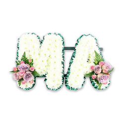 A lovingly crafted funeral letter tribute forms the word MA in bold, upright capitals, captured as a studio-style image on a pure white background so that every floral nuance is visible. The letters themselves are completely filled with compact white chrysanthemums, each bloom neatly nestled against the next, creating a plush, cushion-like texture that appears both soft and reassuring to the touch. Along the outer edges, a rich green satin ribbon is folded into gentle pleats, tracing the contours of the M and the A with a crisp, defined line. This verdant frame offers contrast and depth, echoing the leafy avenues and gardens around Golders Green, from Temple Fortune to Childs Hill. At the base of the left leg of the M and the right leg of the A, carefully placed accent sprays introduce colour and emotion. Here, dusky lilac roses mingle with blush-pink roses and delicate pink spray roses, some fully open, others still in bud, suggesting the different stages of a life remembered. Feathery green fern fronds arc lightly around the roses, adding a natural, almost woodland grace. The tribute's balanced symmetry and gentle pastel tones convey serenity and affection, making it an especially fitting choice for honouring a beloved mum or mama. One can imagine this MA floral piece resting by the coffin or on a stand in a local Golders Green service, its white blooms symbolising purity and its roses whispering love, loss, and gratitude in a quiet, fragrant language of their own.