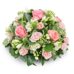 I picture this arrangement as a gentle English garden translated into a compact, domed tribute. Soft pink roses dominate the scene - some large and boldly open with layered, velveteen petals, others as petite spray roses adding tender accents of paler pink - all arranged to create depth and a slow, inviting rhythm. White freesias are woven through like bright notes of piano: slender, bell-shaped flowers, some open and showing pale yellow stamens, others in elegant bud form, promising to loosen into further beauty. The greenery supports and sculpts the round form; deep, glossy leaves provide weight and structure while cream-edged variegated foliage lifts the lightness of the palette and introduces delicate contrast without distracting from the blooms. There are no visible stems, only a smooth, rounded profile that reads formal and refined under soft daylight, which highlights the subtle sheen of petals and the fresh, springlike scent of freesia.

As a florist working near Golders Green I think of this piece both for quiet celebrations and comforting remembrance: it sits easily on a mantel at a small family gathering or at the front of a chapel service close to Finchley Road. The tactile mix of velvet rose petals and crisp greenery, combined with the discreet, evocative fragrance of freesia, is designed to comfort and to remember - a bouquet made to feel personal, fresh, and thoughtfully crafted by hands that know the local rhythms of Golders Green mornings.