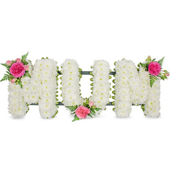 A lovingly crafted "MUM" tribute stretches horizontally across the image, the three block letters resting on a discreet dark green frame that hints at the sturdy support beneath the blooms, much like the quiet strength of families gathering in Golders Green during times of loss. Each letter is densely covered with small white chrysanthemums, every floret pressed closely to its neighbour so the surface looks like a soft quilt of petals. The white flowers form a smooth, cushion-like texture that suggests peace, purity, and reflection, suitable for display at a funeral service or graveside in one of Golders Green's tranquil cemeteries. Along the upper left edge of the first "M", a vibrant cluster of fuchsia and pink roses introduces a touch of warmth: a large, ruffled garden rose in deep fuchsia takes centre stage, surrounded by paler pink spray roses and delicate green ferns. The "U" holds a similar cluster at its lower central curve, tucked in as if gently cradling a memory, and the second "M" is crowned on its upper right corner with an almost identical grouping, creating a visual rhythm across the word. The fern foliage fans out lightly from each cluster, its fine serrated leaves adding movement and a natural, garden-fresh feel reminiscent of nearby parks and green spaces. Against the plain white background, the tribute appears almost to float, drawing the eye straight to the loving word "MUM." This arrangement quietly conveys respect, tender gratitude, and remembrance, reflecting the sensitive craftsmanship you would expect from an experienced Golders Green florist.