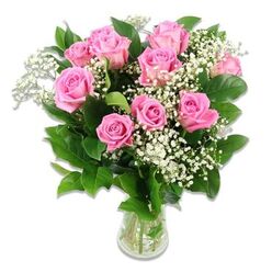 A softly radiant bouquet of ten to twelve pink roses is captured in front of a pristine white background, every bloom arranged to create a sense of calm delight and affectionate warmth. The roses themselves are the stars of the composition: some fully unfurled with velvety petals spiralling outward in shades from pale blush to a richer mid-pink, others still partially closed, hinting at new petals yet to open. Scattered among the roses, delicate sprays of white baby's breath appear like tiny snowflakes or airy clouds, filling the spaces between stems and giving the arrangement a gentle, floating lightness. Surrounding and supporting the flowers, glossy dark green leaves provide a deep, natural frame, making the pinks and whites seem even more luminous. The bouquet sits in a simple, clear glass vase with clean lines, the stems visible in the clear water, adding a reassuring sense of freshness and professional care. The bright, even lighting resembles daylight streaming into a Golders Green townhouse, making every detail crisp without harsh shadows. This floral design feels especially suited to baby celebrations in the local area-perhaps a sweet centrepiece for a naming day near Golders Hill Park or a welcoming gift delivered to new parents around Temple Fortune. Its soft pink palette expresses tenderness, gratitude, and quiet joy, ideal for articles exploring baby girl bouquets, thoughtful maternity gifts, nursery florals, or the role of roses and Gypsophila in marking life's first precious moments within the Golders Green community.