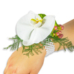 A graceful wrist corsage rests on a fair-skinned wrist against a pure white backdrop, a study in quiet elegance and texture. At its centre sits a single large white Phalaenopsis orchid, petals broad and satiny, their surface catching a soft, even light so the bloom reads like carved porcelain. The orchid's labellum carries a concentrated splash of bright yellow with deeper orange shading at the throat, drawing the eye to the bloom's intimate centre. Around the orchid a nest of feathery asparagus-fern fronds fans outward in fresh, vibrant green, their fine threads creating a whisper-soft contrast to the orchid's smooth planes. To the upper right, a small cluster of glossy Hypericum berries arcs gently from pale green through warm rose to cranberry-red, a tiny progression of ripeness that introduces a late-summer warmth. A few ruffled, lime-green accent leaves tuck in beside the berries, adding a crisp, contemporary note of colour and movement. The whole composition is anchored to the wrist by several strands of tiny, lustrous white pearls, their cool sheen and rounded rhythm lending heirloom poise and a secure, comfortable fit. The photograph's bright white setting strips away distraction so you can study surface, hue, and form: the orchid's faint floral scent imagined, the fern's soft give, the berries' glossy tautness and the pearls' smooth glide against skin. This refined corsage reads as timeless and romantic-perfect for a prom or wedding in North London, a delicate accessory for a bride or guest leaving Golders Hill Park or arriving at Golders Green Tube in the soft light of celebration.