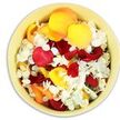 A top-down view focuses on a softly rounded ceramic bowl in a pale, buttery yellow tone, its interior completely filled with a carefully gathered mix of petals designed as a gentle funeral tribute. Dominating the surface are rose petals in rich, saturated hues: velvety crimson and wine red mingle with bright sunshine yellow and soothing shades of peach and apricot, creating a warm, comforting palette. Threaded between these larger, silky petals are numerous tiny white florets, likely hydrangea, their slightly ruffled, paper-fine texture providing a cool contrast that lightens the overall effect. The petals lie in an easy, organic tumble, with no harsh lines or rigid structure, evoking the sense of petals scattered by hand in a moment of quiet remembrance. Soft, even lighting reveals the curves and folds of each petal, while gentle shadows between them add depth without disturbing the calm mood. Visually, the image suggests subtle fragrance-a blend of sweet rose and airy, fresh hydrangea-that might drift through a still room after a service. This petal-filled bowl would sit beautifully beside a framed photograph at a memorial reception in Golders Green, or on a console table near the entrance of a local chapel as mourners arrive. It feels rooted in the neighbourhood's understated elegance, like something a thoughtful florist working close to the Golders Green station might prepare for families who prefer a softer, more symbolic expression of farewell rather than bold wreaths, offering a quiet gesture of love, gratitude, and peaceful release.