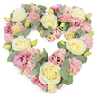 A densely layered, heart-shaped floral wreath appears against a bright white background, its pastel flowers forming a clear, emotional focal point. The heart is constructed from an abundance of creamy ivory and pale yellow roses, their petals tightly formed yet lush, each one opening like a quiet sigh. Between these main flowers, clusters of light pink carnations weave through the design, their frilled edges providing a soft, almost cushiony texture that enhances the feeling of tenderness. Deeper pink and mauve lisianthus blossoms are tucked into the composition, some more open and revealing, adding glimmers of richer colour and a slightly more contemporary feel alongside the traditional roses and carnations. Cool, silvery-green eucalyptus foliage threads throughout the wreath, its rounded leaves resting against the petals and giving the arrangement a fresh, calm, and gently aromatic presence. Small yellow-green buds dot the design, suggesting that some blooms are still to come, and subtly symbolising hope alongside remembrance. The overall effect is of a complete, balanced heart, rich with flowers and emotion yet soft in tone. For families in Golders Green arranging funeral flowers or sympathy tributes, this is the sort of design that often rests beside a coffin or at a graveside, especially around Golders Hill Park and the nearby quiet streets, where people seek a tribute that conveys love without harsh colours. The pastel shades, dense florals, and carefully shaped heart speak of enduring affection, cherished memories, and a wish to offer comfort during times of grief and farewell.