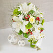 On a clean white tabletop, a lavish floral arrangement unfolds in calm whites and fresh greens, accented with just enough colour to feel joyful, like a celebration in one of Golders Green's elegant townhouses. At its core, wide-petalled white Oriental lilies open in full bloom, their satin petals curling back to reveal speckled throats and prominent stamens. Nestled beside them is a beautifully composed yellow rose, its tightly layered petals swirling outward in a soft, creamy spiral that adds a gentle glow. Throughout the bouquet, airy clusters of white baby's breath float between the larger blooms, creating a misty, romantic veil. Rounded tufts of bright green dianthus, reminiscent of miniature moss balls, add playful texture and a garden-fresh look. Fine, light green foliage reaches in different directions, softening the silhouette and lending the arrangement a relaxed, natural grace. Scattered among the greens are polished red hypericum berries, like tiny garnets catching the light, adding a subtle festive note that would suit a winter wedding near Golders Green Station just as beautifully as a summer celebration. Along the right side of the design, a cascading line of white Phalaenopsis orchids drapes elegantly downward, each orchid blossom pristine and smooth, with hints of yellow in the centres and clusters of unopened green buds at the tips. The flowers are cradled in a white woven basket, its subtle pattern echoed in two decorative white wicker spheres placed on the table nearby. This sophisticated composition feels perfect for a wedding reception, civil ceremony, or special event in Golders Green, offering a refined, contemporary take on classic white-and-green florals.