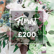 From the heart of Golders Green, this Florist Choice bouquet sits as a quiet celebration of refined floral design. The elegant cluster is set in a clear vase, the arrangement radiating softness and premium craftsmanship. The palette blends soft pastel tones with muted greys, creating a luxurious, contemporary feel that suits weddings, anniversaries, or a thoughtful gift. Dominant blooms include delicate, fully open light pink garden roses whose petals unfurl like satin, white anemones with their signature dark centers, and subtly purple-grey roses that add a modern note to the composition. Spiky, globular blue eryngium thistles punctuate the arrangement, introducing a cool contrast and architectural edge that keeps the bouquet lively rather than predictable. Around and through the blooms, lush greenery threads the design: slender eucalyptus-like leaves provide a silvery gloss, while deeper burgundy or maroon leaves offer a touch of drama and depth. In the center, a semi-transparent white rectangular overlay rests against the blooms, clearly displaying Florist CHOICE followed by the bold and inviting ?200. This little rectangle acts like a whisper of branding, letting the flowers speak for themselves while still guiding the eye to the price and option. The overall composition feels natural and substantial, suggesting a bespoke service crafted by an experienced Golders Green florist. The soft, naturally lit background hints at an outdoor setting or sunlit studio, ensuring every petal, vein, and texture reads clearly. It is a bouquet designed to convey celebration and elegance, a premium gift ready for a wedding, an anniversary, or a heartfelt gesture delivered with same day availability across Golders Green and the surrounding neighbourhoods.