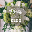 A luminous white-and-lime arrangement stands out in a softly blurred setting, a Florist Choice bouquet that radiates contemporary elegance. At its core are pristine white lilies, their petals unfurling with a satin-like sheen, surrounded by generous clusters of smaller white blossoms that add cloudlike fullness. Lime-green accents punctuate the design-textured spheres and blocks of color, likely Green Trick dianthus or compact hydrangeas-creating a bright, modern contrast against the white bloomscape. The greens are rich and varied, with eucalyptus and ruscus weaving through to give depth and a natural, garden-fresh feel. The bouquet appears hand-tied, held by a person whose pale attire is just hinted at in the background, suggesting a moment of preparation before a celebration near Golders Green. Centered in the frame, a crisp white overlay carries the branding-Florist Choice Bouquet-rendered in elegant script with the word BOUQUET in uppercase beneath, and the price £200 in a bold, easy-to-read type. The overall look is luxurious but accessible, designed for same-day delivery across Golders Green and nearby districts, appealing to someone choosing a thoughtful, high-value gift for a wedding, anniversary, or milestone. This image reflects the craft of a dedicated North London florist, a promise of freshness, style, and reliable service that serves the local community from NW11 to the broader surrounding streets.