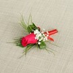 A single, exquisitely crafted boutonnière lies diagonally across a softly textured, light beige fabric, the material reminiscent of natural linen one might see in a chic Golders Green bridal boutique. At its heart is a tightly furled fuchsia rosebud, the petals rich and velvety, holding the promise of full bloom without yet revealing all their layers. The deep pink tone leans toward magenta, glowing warmly against the neutral background and drawing the eye instantly to its romantic focal point. Cradling the rose are tiny clusters of pure white baby's breath, each miniature blossom like a cloud of froth, softening the intensity of the rose and adding a delicate, lace-like halo around it. Slender, feathery sprigs of bright green foliage, similar to asparagus fern or fine ruscus, fan out behind the bloom, giving the buttonhole a light, airy silhouette, as if it has been gathered fresh from a garden walk near Golders Hill Park on a clear morning. Beneath the flowers, the stems are neatly bound in a thin, glossy red satin ribbon, wrapped smoothly and tightly to form a compact handle that ends in a small, tidy finish rather than a large bow, adding just a touch of shine and refinement. The lighting is bright yet gentle, catching the sheen of the ribbon and the subtle curves of each petal, making the arrangement appear crisp and freshly made, ready to be pinned to a groom's lapel for a Golders Green wedding, a prom night, or any formal celebration where a single rose can quietly speak of tenderness, love, and timeless elegance.