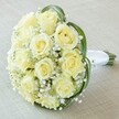 In the gentle light that often fills Golders Green homes, a stately bridal bouquet takes centre stage on a pale linen surface, every detail meticulously considered. Central to the design is a generously clustered array of creamy, pale yellow roses-some whispering the secrecy of new beginnings, others blooming confidently with soft, unblemished petals. These sumptuous blossoms are harmoniously interlaced with sprays of airy baby's breath, their tiny star-like flowers unfurling a light, cloud-soft layer around the roses and bestowing an ethereal feel. Encircling the bouquet, graceful ribbons of gleaming dark green foliage swoop with sculptural elegance, providing striking contrast and contemporary flair reminiscent of Golders Green's blend of classic and modern styles. The stems, neat and uniform, are gathered and wrapped in lustrous white satin ribbon, forming a poised, tactile handle for ceremonies and celebrations alike-perfect for a bride preparing to walk along the tranquil avenues of NW11. The fragrance is subtle yet evocative, hinting at open gardens and quiet devotion-a bouquet that radiates purity, romance, and enduring sophistication, thoughtfully assembled for weddings, anniversaries, or meaningful gatherings across Golders Green.