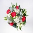 A lush hand-tied bouquet overflowing with romance and optimism, captured as if resting on a sunlit table in a cosy Golders Green home. Deep crimson roses with velvety petals create a passionate heart to the design, surrounded by vivid pink-red carnations whose softly ruffled edges feel almost feathery to the touch. Snow-white daisies and daisy-like chrysanthemums cluster around them, their bright yellow centres giving a gentle, morning-light cheerfulness. Fine sprays of gypsophila, or baby's breath, float between the larger blooms like tiny white stars, adding an airy, celebratory lightness. Eucalyptus leaves arc gracefully through the bouquet, their cool blue-green tone and matte texture contrasting with glossy tropical foliage in deeper greens, giving the arrangement a modern, stylish frame. From above, the bouquet appears beautifully rounded and balanced, neither formal nor wild, as though shaped by confident, experienced hands that regularly craft gifts for birthdays and reunions along Finchley Road and near Golders Hill Park. You can almost sense the soft rustle of leaves and the gentle mingling of fragrances: the warm, familiar scent of roses, the subtle spice of carnations, and the fresh, herbal whisper of eucalyptus. This arrangement feels like the start of a bright new day, perfect for welcoming someone home to a flat near Golders Green station or brightening a favourite reading corner. Every stem seems chosen to convey affection, congratulations, and quiet joy, a bouquet that holds both comfort and excitement in its harmonious blend of colour, texture, and form, inviting you to pause and simply enjoy the presence of fresh flowers.