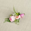 Resting upon a lightly textured beige linen, this hand-crafted boutonniere from the heart of Golders Green showcases refined expertise and heartfelt artistry. The central rose, its petals in pale pastel pink, remains tightly furled in a graceful spiral, evoking a sense of freshness and hope. Next to it, a soft, peach-tinted bloom opens gently, its yellow accents and subtle freckles providing intricate detail reminiscent of the delicate flora in Golders Green Crematorium's formal gardens. Snowy sprigs of baby's breath and verdant orbs of cushion mum are carefully tucked between-adding both airiness and boldness to the arrangement. Lush green foliage in varied shapes and textures, including slim grass blades and broad leaves, are meticulously arranged for depth and structure; one wide, dark leaf is elegantly wrapped around the base, lending a polished finish. The bouquet is bound with a glossy, fuchsia pink satin ribbon, tied into a delicate bow, which adds a touch of festivity and draws the eye with its lustrous finish. Gentle, natural daylight casts soft shadows and highlights each detail, bringing out the subtle tones and crisp texture of the background fabric. This bespoke accessory captures the romance and grace suited for special occasions across the NW11 community-from intimate wedding ceremonies to elegant proms-offering a whisper of Golders Green sophistication in every petal.