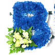 A large floral tribute in the distinct shape of a capital B dominates this image, designed with the quiet formality often requested for funerals in the Golders Green area. The body of the letter is densely filled with royal blue chrysanthemums, each flower carefully placed so their textured, ruffled petals overlap and form a continuous, plush surface. The colour is an intense, regal blue, with gentle variations in shade that add a sense of depth, as though the letter were carved from blue velvet. A crisp, pleated white satin ribbon surrounds the entire outline of the B and follows its internal curves, lending clear definition and a refined finish that glows softly against the plain white background.   

Nestled into the lower left side of the letter is a smaller, complementary floral cluster that adds softness and sentiment. Here, creamy white roses-some tightly closed, others beginning to open and reveal their swirling centres-are arranged closely together, giving the impression of tenderness and care. Between them, sprays of small white chrysanthemums, reminiscent of tiny daisies, introduce lightness and a touch of delicate texture. This cluster is framed by a generous collar of greenery: arching fern fronds, glossy dark leaves, and lighter, slightly variegated foliage provide contrast and a natural, garden-like feel. The combination of cool blue, clean white, and fresh green makes the tribute feel composed and serene. It reads as a personalised initial that could represent a first name or surname, an elegant way to say a final goodbye at a funeral, memorial service, or private remembrance gathering in and around Golders Green.