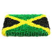 A bold rectangular floral display interprets the Jamaican flag with vivid clarity, each section formed entirely from densely arranged flowers that create a soft, almost quilted surface. Against a pure white background, the tribute's colours appear exceptionally bright and true. A diagonal golden-yellow cross dominates the center, its lines perfectly straight and balanced, built from countless small yellow blooms whose petals curl and overlap like tiny ruffled ribbons. This radiant saltire divides the arrangement into four triangles. The upper and lower triangles are made from rich green chrysanthemums and similar button-like blossoms, tightly packed so they form a smooth, plush field of colour with delicate shadows between the petals. On the left and right, the triangles are filled with deep black flowers or petal clusters, giving a velvety, almost matte finish that absorbs light and sets off the green and yellow with dramatic contrast. The tribute is clearly dimensional, standing proud from its base, more akin to a floral artwork than a simple wreath. You can imagine a gentle, leafy fragrance rising from the fresh greenery, softening the atmosphere of a chapel or family home. Crafted for moments of farewell, this design carries strong cultural meaning, making it an especially poignant choice for families around Golders Green wishing to honour Jamaican roots at a funeral or memorial. The even, bright lighting in the image highlights the careful symmetry and craftsmanship, reflecting the quiet respect and pride that go into creating such a personalised symbol of remembrance.