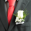 Nestled into the lapel with practiced care, this elegant boutonnière centers on a creamy white rose whose petals form a soft, serene spiral. Surrounding it are airy sprays of baby's breath, their tiny, cloud-like blooms lending an ethereal lightness that balances the rose's gentle density. Curved slivers of dark green foliage and slender fern-like twigs arch around the flower, creating a natural frame that gives the arrangement contrast, depth, and movement. At the base, a delicate white ribbon is tied into a modest bow, its satin sheen catching the daylight that filters through the shop window on Golders Green Road. The overall mood is cool and tranquil-visual calm amplified by the contrast of snow-white petals against a charcoal jacket-an impression I often aim for when preparing pieces for church weddings, civil ceremonies, or commemorative occasions near the Northern Line station. As a local florist I take care with texture: the velvet touch of the rose, the feathery whisper of gypsophila, and the crisp resilience of fresh foliage, all chosen to stay fresh through a full day of photos and travel across Finchley Road. This boutonnière is made with secure wiring and neat taping to sit straight on a lapel, offering both ceremony and comfort. Arranged professionally by Flowers Golders Green, it feels like a quiet promise-honourable, thoughtful, and perfectly suited to someone stepping into a meaningful moment in our neighbourhood.