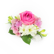 Against a pristine white backdrop, a compact, couture corsage sits like a small promise: at its centre a plush, bubblegum-to-fuchsia pink rose whose tightly coiled inner petals gradually unfurl into a soft, velvety bloom. Around the rose a halo of pastel pink and lavender hydrangea florets creates gentle volume, their wafer-thin petals layered like a whisper of spring. Interspersed among these are creamy white, trumpet-shaped blooms-small alstroemeria or amaryllis-like flowers-with delicate greenish throats that catch the light and brighten the composition. Glossy, deep green leaves peek out from the base, their broad surfaces lending weight and painterly contrast, while slender green buds tipped with a hint of yellow lift the eye upward and suggest more life to come. At the bottom right, a small cascade of pearlescent beads clusters together, reflecting the soft studio light and adding a refined, bridal sparkle without overwhelming the natural flowers. The overall texture moves between velvet rose petals, feathery hydrangea clusters, and the satin gleam of pearl-like accents; the scent you imagine is cool and floral, like an early-morning garden visit. This intimate arrangement reads as a wedding corsage or elegant boutonnière for prom night, ideal for celebrations held near Golders Hill Park, in Hampstead Garden Suburb, or at a reception venue along Finchley Road. Crafted with a careful hand and meant to be held close, it evokes quiet joy and timeless romance-a small, tactile keepsake for vows, anniversaries, or milestone dances in and around Golders Green.