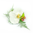 Centered on a pristine white Phalaenopsis orchid, this corsage reads like a quiet poem of refinement. The orchid's broad, satiny petals unfold with a gentle, almost waxy sheen; each petal catches the light and guides the eye toward a warm, detailed throat where soft yellow and honeyed gold blend with tiny hints of light brown, giving the blossom depth and an inner glow. Surrounding and supporting the focal bloom are feathery fronds of asparagus fern that fan leftward and trail down to the right, their fine texture lending a breathy, diaphanous movement as if a light breeze might lift them. To the right sit clustered, round hypericum berries in a warm reddish-pink, their glossy skins offering a cheerful pop of colour against the orchid's purity. Nestled lower, a compact, lime-green chrysanthemum or similar filler adds a bright, verdant counterpoint and a lively textural contrast. The whole composition is intentionally asymmetrical yet balanced, compact enough to pin as a boutonniere or to fasten as an elegant wrist corsage, designed to sit lightly on fabric or skin without overwhelming. Photographed against a clean white background with crisp, natural lighting, every tiny vein, sheen and shadow is visible - from the fern's delicate filaments to the berry's polished highlights - creating an image that feels fresh, deliberate and wearable. As a local piece inspired by celebrations in Golders Green - from intimate synagogue weddings to afternoon gatherings near Golders Hill Park - the arrangement speaks of understated luxury, tactile softness and the gentle kind of joy that quiet, well-made flowers bring.