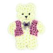 In this photograph, a three-dimensional floral teddy bear sits against a clean white background, a poignant funeral tribute crafted with precision and care for families in Golders Green. The teddy is built entirely from creamy white chrysanthemums, each flower closely packed to form a plush, textured surface that resembles soft toy fur. The rounded shape of the head, ears, body, and paws is clearly defined, with gentle shading between the blossoms giving the bear a sculpted, almost huggable presence. Two small, dark floral centres create bright, button-like eyes, while a similar darker bloom forms the nose, together with a delicately curved line of petals that hints at a tender, reassuring smile. Across the chest, a waistcoat of rich purple and lilac flowers introduces a dignified splash of colour, the petals arranged to show a clear V-shaped opening and neat lapels, like a tiny jacket carefully dressed before a service near Golders Green Crematorium or a chapel along Finchley Road. Around the neck, a soft lavender mesh bow is tied, its sheer loops resting lightly over the floral fur, adding a touch of grace and gentle formality. The colour palette-creamy white, deep purple, and pastel lilac-creates a mood of innocence, serenity, and loving remembrance. Although no other objects appear in the image, you can imagine this teddy bear placed beside a coffin or at the front of a memorial, the fresh, green scent of chrysanthemums offering a quiet sense of peace. It is a deeply personal sympathy arrangement, often selected to honour a child or to evoke the tender, childlike qualities of someone dearly missed in the Golders Green community.
